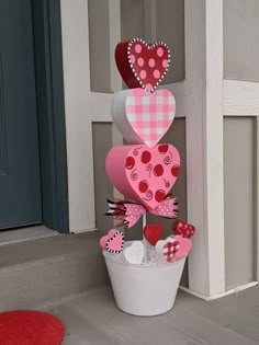 a potted plant with paper hearts hanging from it's sides on the front porch