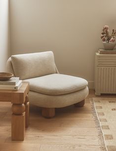 a living room with a chair, table and rug on the floor in front of a window