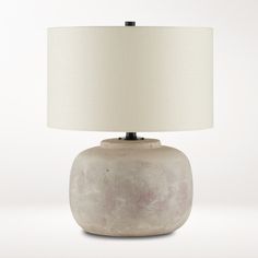 a table lamp with a white shade on the base and a beige drum light in front of it