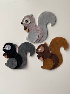 four felt squirrels are sitting on top of each other