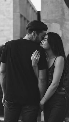 black and white photograph of a man kissing a woman's forehead on the street