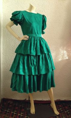 Materials: green silky polyester dress 80s extravagant ruffled dress, emerald jacquard dress, puffy sleeve, princess dress, edwardian victorian style dress, ruffled dress, big ribbon decoration on the back,deep V on the back, probably is handmade, probably the dress is made by silky polyester. very good vintage condition but the item is not dry clean. Please check the measurements before ordering : shoulders :39 cm (15,5 inches) bust:41 cm (16 inches) waist :37 cm cm (14,5 inches) total lenght:120 cm (47 inches) sleeve lenght:34 cm (12 inches). Elegant Green Dress With Tiered Skirt, Elegant Green Tiered Skirt Dress, Green Ruffled Skirt Evening Dress, Green Ruffled Skirt Dress For Evening, Green Ruffled Dress For Costume Party, Fitted Green Ruffled Dress, Fitted Green Dress With Ruffles, Green Fitted Dress With Ruffles, Fitted Green Dresses With Ruffles