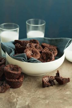 chocolate cookies and milk are on the table next to two glasses with milk in them