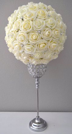 a bouquet of white roses sitting on top of a silver stand