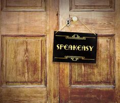 a wooden door with a sign hanging from it's side and the words speakensy written in black