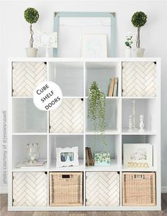 a white bookcase with green stencils on the front and bottom, along with wicker baskets