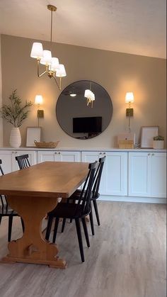 a dining room table with four chairs and a large mirror on the wall above it