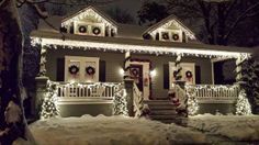 a house covered in christmas lights with wreaths on the front porch and steps leading up to it