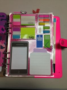 an open pink notebook with lots of stickers and writing on the pages next to a cell phone