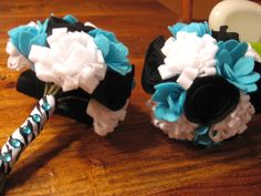 two wedding bouquets made out of black, white and blue flowers on a wooden table