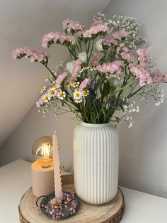 a vase filled with flowers sitting on top of a wooden table next to a candle