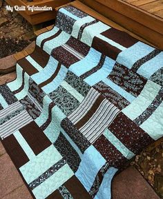 a blue and brown quilt sitting on top of a wooden bench