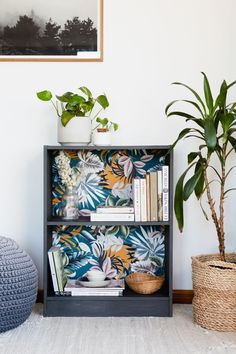 a book shelf with books and plants on it next to a potted plant in a basket