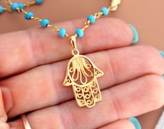 "This is a gorgeous multi-strand necklace made of 3mm faceted Turquoise gemstones on 24kt gold veril. Necklace layers measure 16\"-18\" or 18-20\" with a 18kt gold filled Hamsa pendant that measures 3/4\". Beautiful gold rose beads accent this lovely necklace. Necklace comes nicely boxed for the perfect gift! Turquoise absorbs negativity, promotes honest & clear communication from the heart & is an excellent grounding stone. Good for healing the spirit & soul, it is known as a master Spiritual Gold Turquoise Necklace With Gemstone Beads, Gold Turquoise Necklace With Gemstone Beads For Spiritual Style, Spiritual Turquoise Necklace With Lobster Clasp, Handmade Gold Turquoise Necklace With Round Beads, Gold Turquoise Necklace With Round Beads As A Gift, Gold Turquoise Necklace With Round Beads For Gift, Gold Turquoise Necklace With Tiny Beads In Bohemian Style, Gold Turquoise Necklace With Lobster Clasp, Gift, Handmade Dainty Gold Turquoise Necklace