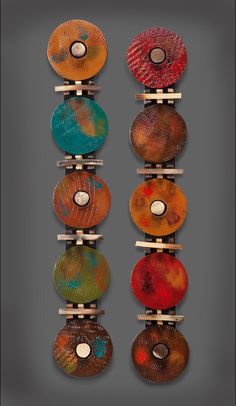 several different colored discs are hanging on a wooden rack in front of a gray background