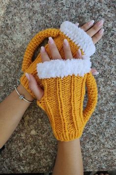 a woman's hand holding a yellow knitted mitt on top of a floor