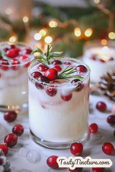 two glasses filled with drinks and garnished with cranberries on a table