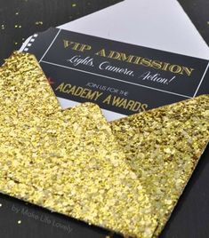 a gold glitter envelope with a black and white business card inside that is open to reveal an award