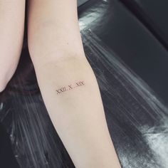 a woman's arm with the word xxvix tattooed on her left arm