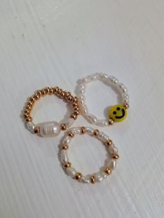 Freshwater pearl stretch bead rings. Three different styles. Freshwater pearls and smiley face. Freshwater pearls and gold glass seed beads. Large  Freshwater pearl and gold glass seed beads  Stretchy.  Sizes  5/6/7  cms. S/M/L Made using strong 5mm crystal stretch elastic. Super cute and ideal to wear on its own or as stacking rings. Trendy Inelastic Round Beaded Jewelry, Trendy Round Pearl Jewelry, Trendy White Beaded Rings, Trendy Pearl White Beaded Jewelry, Trendy Pearl White Round Bead Jewelry, White Beaded Pearl Ring, Adjustable Trendy Pearl White Jewelry, Cute Pearl Jewelry With Colorful Beads, White Pearl Rings With Round Beads