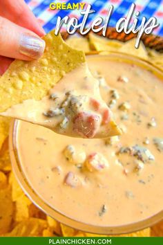 a hand holding a tortilla chip and dipping it into a bowl of creamed dip