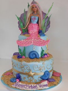 a birthday cake with a barbie doll sitting on it's top and under the seaweed