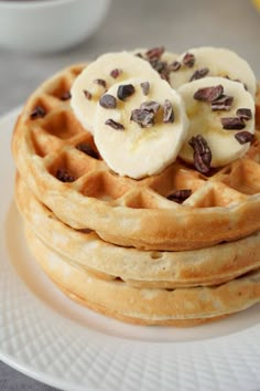 a stack of waffles topped with bananas and chocolate chips on a white plate