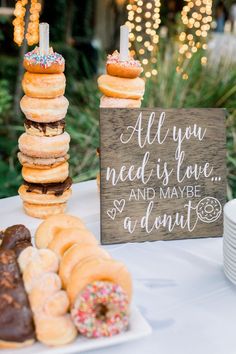 a table topped with lots of donuts next to a sign