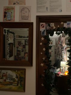 two framed pictures hang on the wall next to a mirror with christmas decorations around it