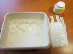 a square white bowl with ice cubes in it next to a bottle of milk