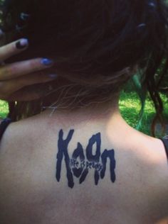 the back of a woman's neck with black ink on it that says koon