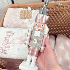 a hand holding a toy in front of a basket with towels and blankets on it