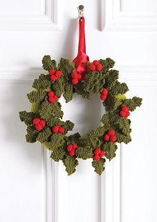 a crocheted christmas wreath hanging on a door