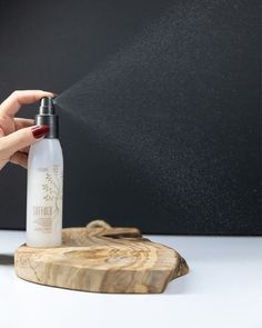 a person sprays water from a bottle on top of a piece of wood