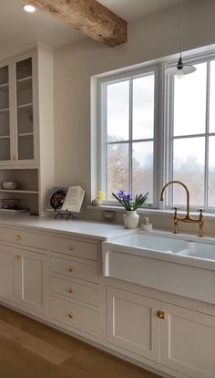 a kitchen with white cabinets and gold faucets in the window sill above the sink