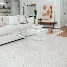 a glass coffee table sitting on top of a rug in front of a white couch