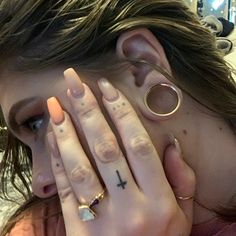 a woman covering her face with both hands and wearing gold rings on her left hand