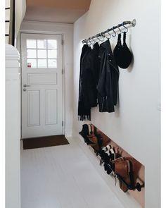 a coat rack with hats and purses hanging from it's hooks next to a white door