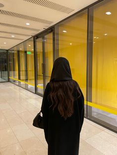 a woman in a black hoodie is walking down the street with her back to the camera