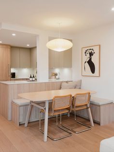 a dining room table with four chairs and a bench in front of the kitchen counter