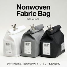 three bags with labels on them sitting in front of an advertisement for nonwoven fabric bag