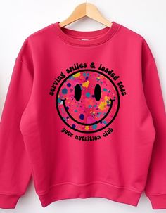 a pink sweatshirt with an image of a smiley face on the front and words saying friends smiles & laughs