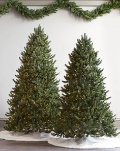 three artificial christmas trees in front of a white wall