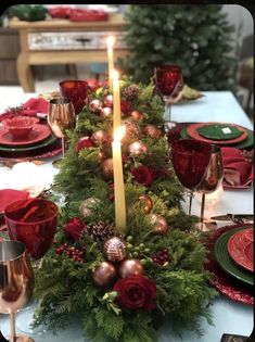 a christmas table setting with candles, plates and napkins on top of the table