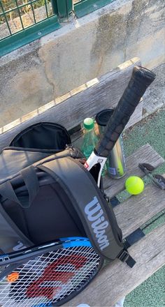 a tennis racket and bag sitting on a bench