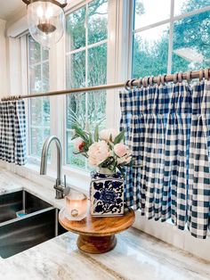 a kitchen sink and window with blue checkered curtains