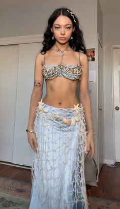 a woman in a blue skirt and top with chains on her waist is posing for the camera