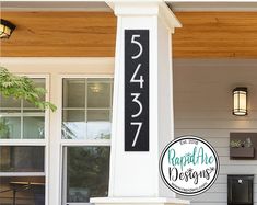 a house number sign sitting on the side of a white building next to a mailbox