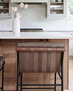 a kitchen counter with two stools and a vase on it's shelf above the bar