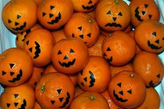 a pile of oranges with jack - o'- lanterns painted on them sitting next to each other